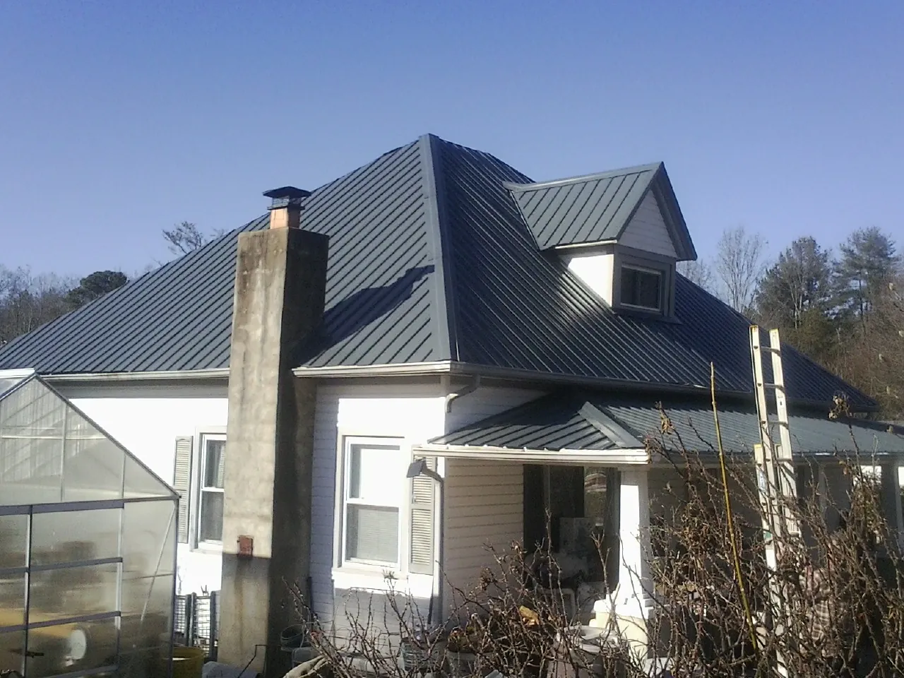 Dark blue standing seam metal roof on a white farmhouse with dormer — Slate & Tile Roof Repair by Roofing Brothers in Chesapeake