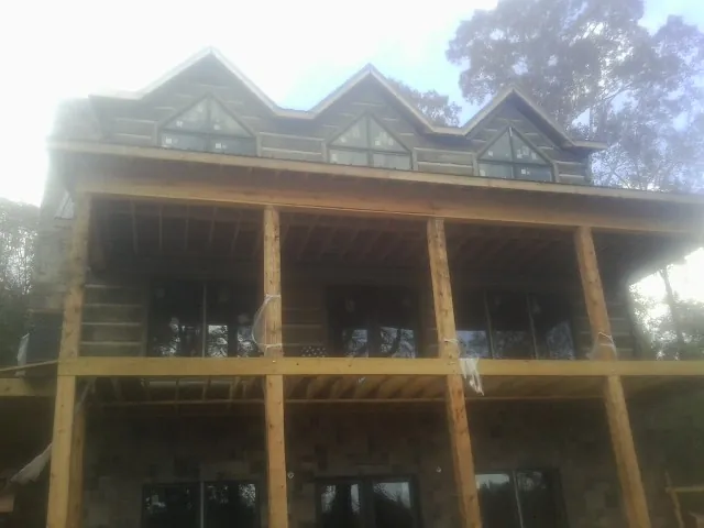 Dormers and porch framing on a large log home under construction — Roof Coating work by our crew in Chesapeake