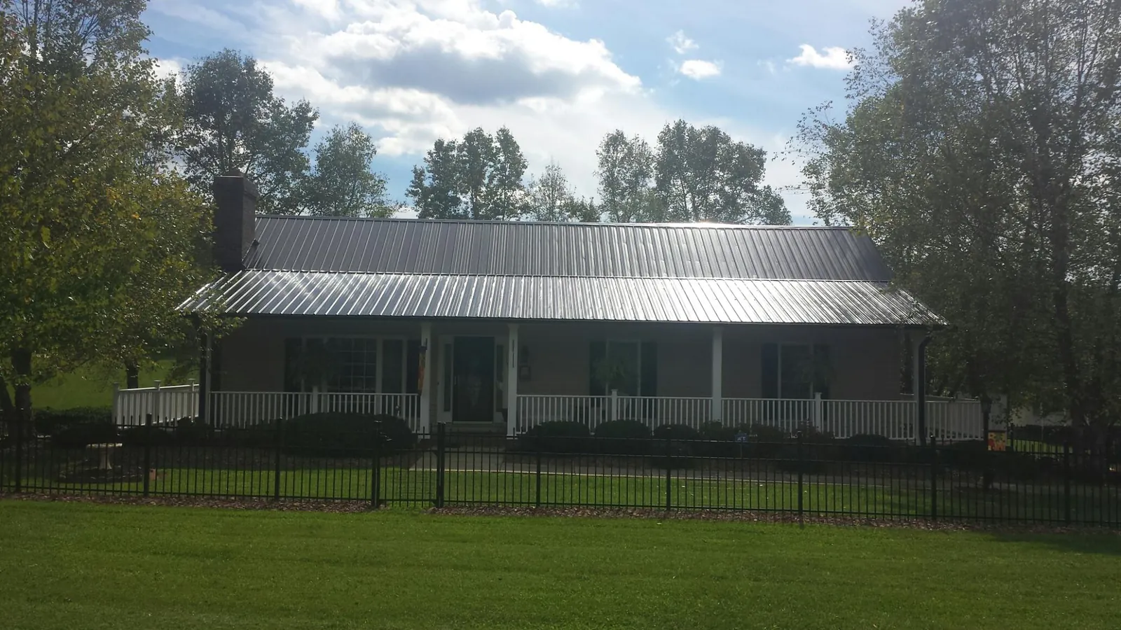 Gray metal roof on a brick ranch with a full width front porch — Gutter Guard Installation work by our crew in Chesapeake