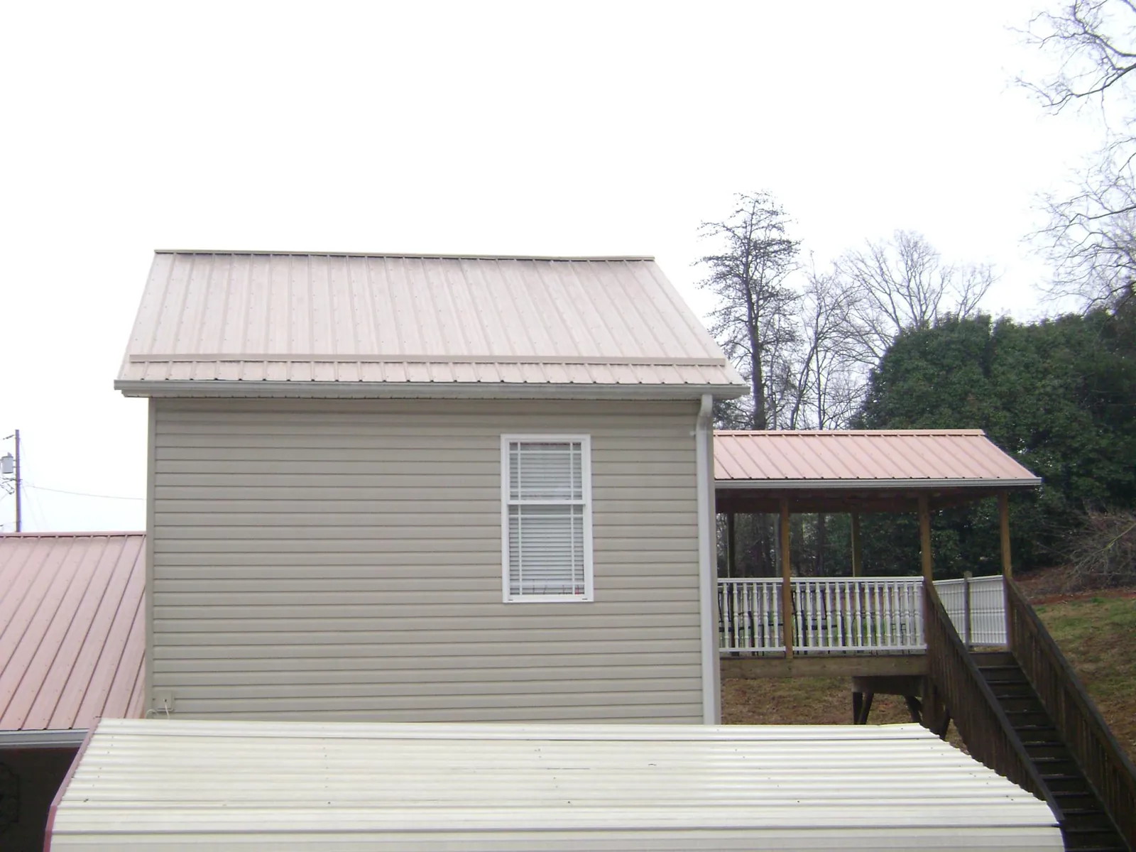 Tan metal roofs on a two story addition and attached porch, from a Roof Replacement job in Chesapeake