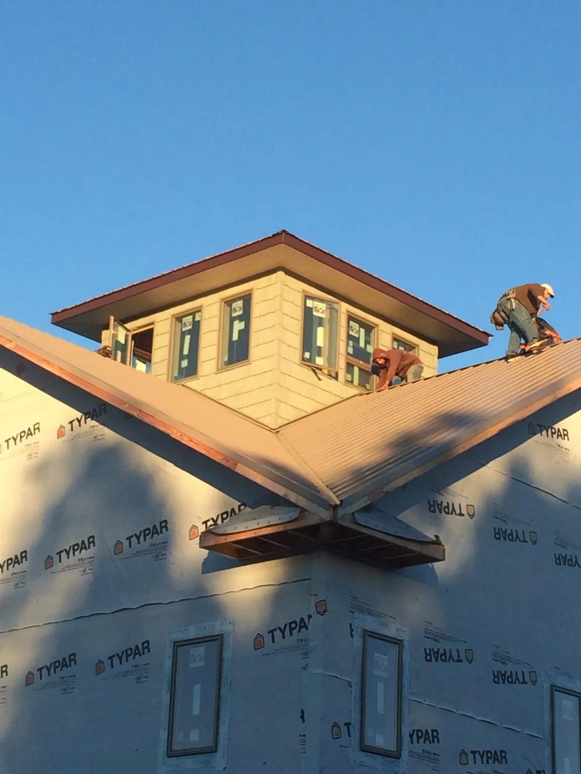 Roofers working around a rooftop cupola on a new metal roof at sunset — Roof Waterproofing in Chesapeake by Roofing Brothers